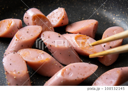 魚肉ソーセージ(斜め切り)をフライパンで炒める調理シーン。(ブラックペッパー炒め) 魚肉ソーセージ(斜め切り)をフライパンで炒める調理シーン。(ブラックペッパー炒め) 108532145