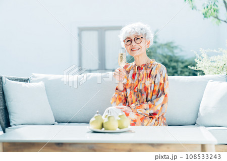 自宅の庭でシャンパンを飲むシニアの女性　 108533243