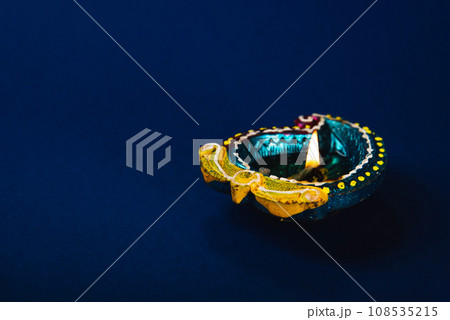 Diwali and Holi celebration concept with vibrant clay diya lamps, these lamps symbolize prosperity, happiness spirituality. Perfect for festive invitations. Diwali and Holi greetings, blue background. Diwali and Holi celebration concept with vibrant clay diya lamps, these lamps symbolize prosperity, happiness spirituality. Perfect for festive invitations. Diwali and Holi greetings, blue background. 108535215