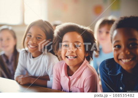 Happy diverse schoolchildren looking at camera. Smiling multiethnic kids posing for group portrait in a classroom of elementary school. Boys and girls of different skin colors go to school together. 108535482