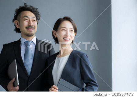 遠くを見つめるスーツ姿で笑顔の男女 安心や信頼のイメージ 遠くを見つめるスーツ姿で笑顔の男女 安心や信頼のイメージ 108537475