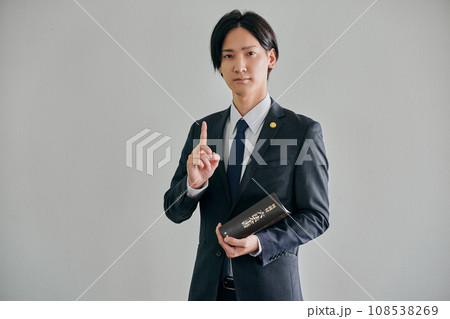 白バックを背景に六法全書を持って立つ男性弁護士 白バックを背景に六法全書を持って立つ男性弁護士 108538269