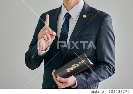 白バックを背景に六法全書を持って立つ男性弁護士 白バックを背景に六法全書を持って立つ男性弁護士 108538270