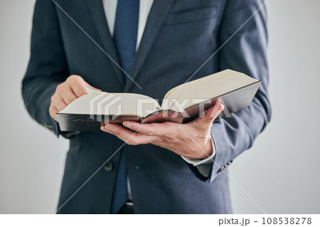 白バックを背景に六法全書を読む男性弁護士 108538278