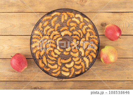 Top view of vegetable and fruit drying section with dried apples and ripe apples on a wooden background. Top view of vegetable and fruit drying section with dried apples and ripe apples on a wooden background. 108538646