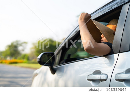 Happy enjoy and freedom in traveling trip with raised hand and holding hat outside of window car in summer vacation holiday. Happy enjoy and freedom in traveling trip with raised hand and holding hat outside of window car in summer vacation holiday. 108539045