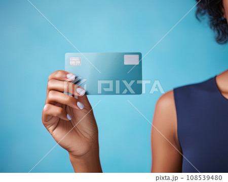 Female hand holding a blue bank card on a blue background AI 108539480