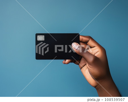 Male hand holding a black bank card on a blue background AI 108539507