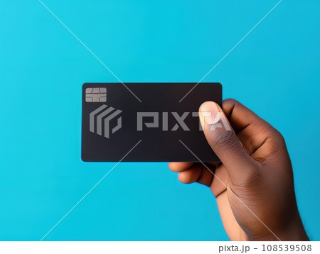 Male hand holding a black bank card on a blue background AI 108539508
