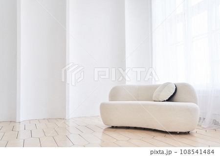 A soft empty white sofa stands on a white background curved by waves, a comfortable fabric sofa stands alone against a white wall, with space to copy. High quality photo 108541484
