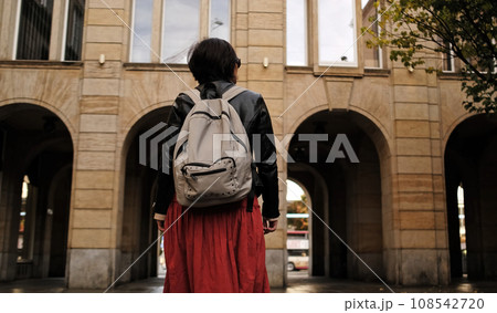 Attractive Woman Walks In City With Backpack, Looking Around Attractive Woman Walks In City With Backpack, Looking Around 108542720