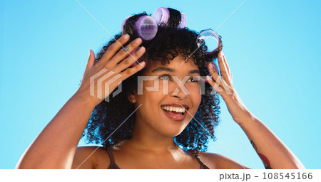 Beauty, smile and woman with roller for hair in studio isolated on a blue background. Curlers, hairstyle and African model at hairdresser salon for natural wellness, cosmetics treatment and thinking Beauty, smile and woman with roller for hair in studio isolated on a blue background. Curlers, hairstyle and African model at hairdresser salon for natural wellness, cosmetics treatment and thinking 108545166