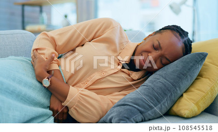 Home, period pain and black woman on sofa with cramps, hurt and injury resting in living room. Sickness, abdominal and upset person holding stomach for tummy ache, menstrual fatigue and constipation Home, period pain and black woman on sofa with cramps, hurt and injury resting in living room. Sickness, abdominal and upset person holding stomach for tummy ache, menstrual fatigue and constipation 108545518