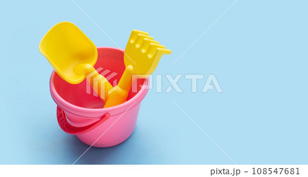 Plastic toys, shovels in bucket on blue background. Summer background concept Plastic toys, shovels in bucket on blue background. Summer background concept 108547681