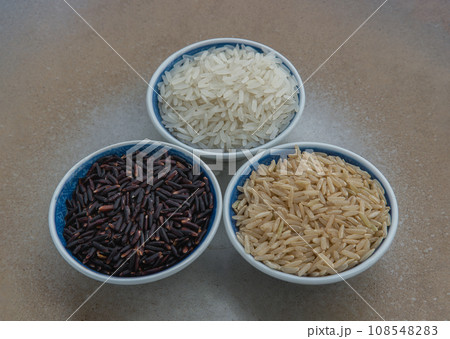 Various types of rice : Brown rice, Jasmine rice, Riceberry on old wooden background. Organic raw rice collection, Healthy food and diet concept. 108548283