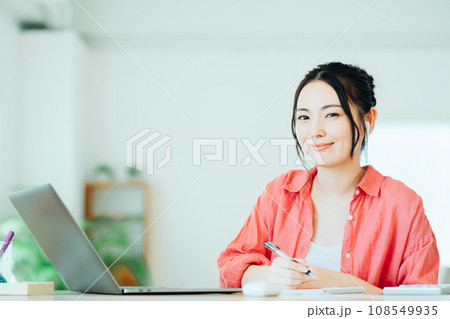 リビングでオンライン学習をする若い女性。 108549935