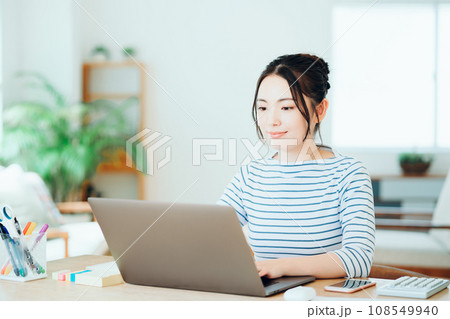 リビングでオンライン学習をする若い女性。 108549940