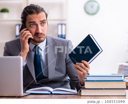 Young male businessman reading books at workplace 108551099