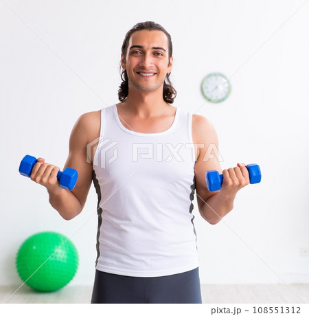 Young handsome man doing sport exercises indoors 108551312
