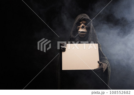 Skeleton, skull, silhouette of a man in a black robe, depicting death holding a blank poster. The 108552682