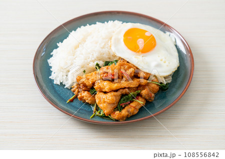 stir-fried fried fish with basil and fried egg topped on rice 108556842
