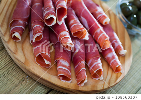 Spanish tapas - rolls of jamon serrano served on wooden board Spanish tapas - rolls of jamon serrano served on wooden board 108560307