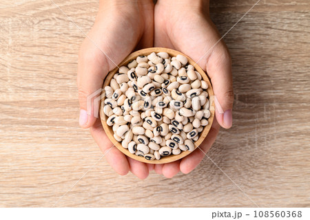 Black eye peas or cowpeas in bowl holding by hand on wooden background 108560368