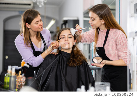Professional women makeup artists applying shadows and blush to young client 108560524