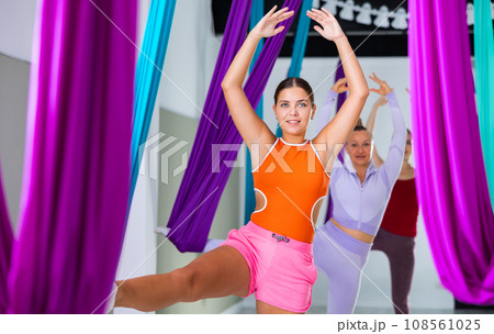 Young yoga woman doing aerial yoga practice in hammock in fitness club 108561025