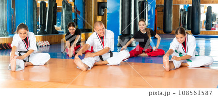 Sporty people in kimonos stretching before martial arts training in gym 108561587