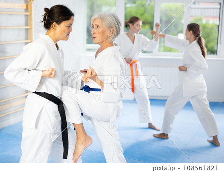 Young and elderly women training karate techniques 108561821