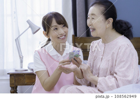 ベッドに腰掛けるシニア女性と苦するの説明をするミドルエイジの看護師の女性 ベッドに腰掛けるシニア女性と苦するの説明をするミドルエイジの看護師の女性 108562949