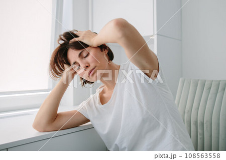 Tired, frustrated, exhausted, stressed woman sitting at desk . Headache. Daylight work.Girl in White tshirt Tired, frustrated, exhausted, stressed woman sitting at desk . Headache. Daylight work.Girl in White tshirt 108563558