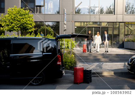 Driver helps a business couple carry their suitcases to the office or hotel Driver helps a business couple carry their suitcases to the office or hotel 108563902