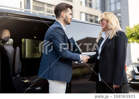 Female chauffeur with a businessman near minivan taxi 108563915