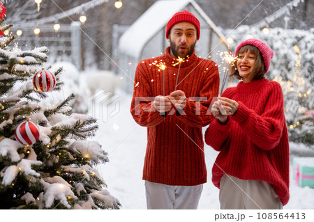 Man and woman celebrate New Year's holidays with sparklers outdoors Man and woman celebrate New Year's holidays with sparklers outdoors 108564413