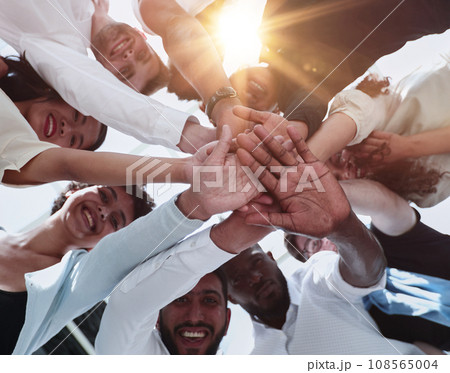 multinational business team looking down putting hands together multinational business team looking down putting hands together 108565004