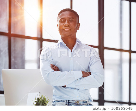 african american man sitting on desk and posing with folded hands african american man sitting on desk and posing with folded hands 108565049