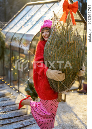 Woman with Christmas tree preparing for a winter holidays outdoors 108565763