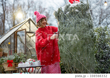 Woman unpacks Christmas tree at backyard 108566332