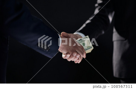 Handshake with the transfer of money on a black background Handshake with the transfer of money on a black background 108567311