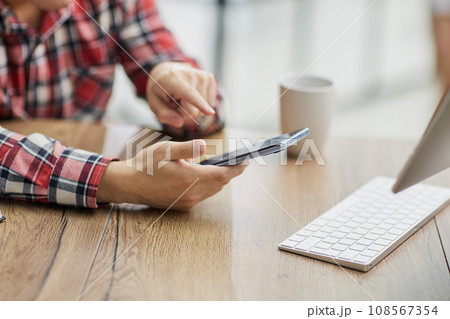 a businessman in the office uses a phone, looks at the screen of a smartphone, browses the Internet 108567354