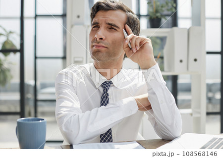 Image of successful businessman 30s thinking and holding index finger at forehead Image of successful businessman 30s thinking and holding index finger at forehead 108568146