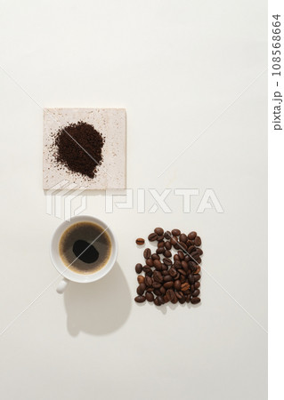 Coffee beans and coffee powder on brick podium decorated with a delicious cup of espresso on white background. Minimalist concept for advertising, natural ingredients for a refreshing drink 108568664