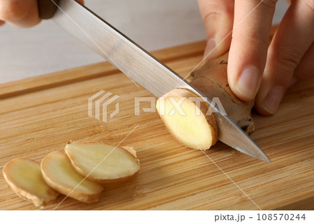 Cutting fresh ginger root on a cutting board 108570244