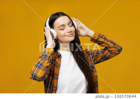 Attractive young woman listening to music in headphones Attractive young woman listening to music in headphones 108570644