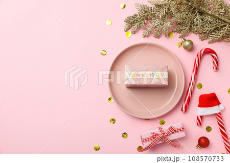 Plate, gift box, Christmas candy canes and decorations on pink background, space for text 108570733