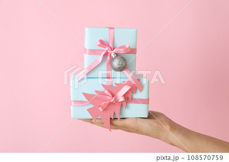 Gift boxes on female hand on pink background Gift boxes on female hand on pink background 108570759