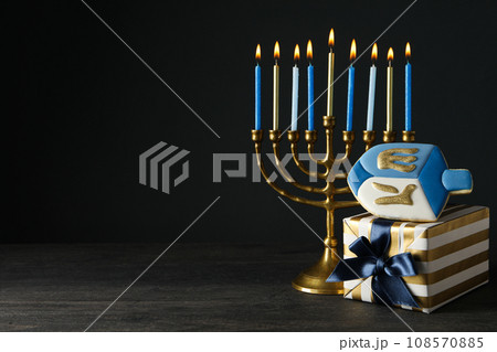 Hanukkiah, gingerbread and gift box on black background, space for text Hanukkiah, gingerbread and gift box on black background, space for text 108570885