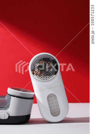 A machine for shaving fabric on clothes, on a red background. 108571233